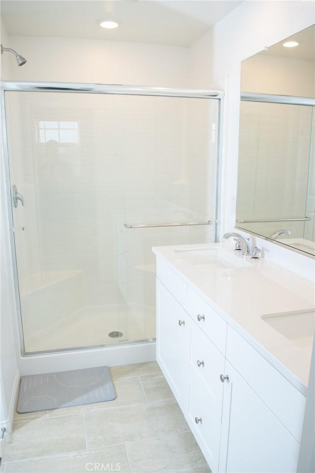 full bathroom featuring tile patterned flooring, double vanity, recessed lighting, a sink, and a stall shower