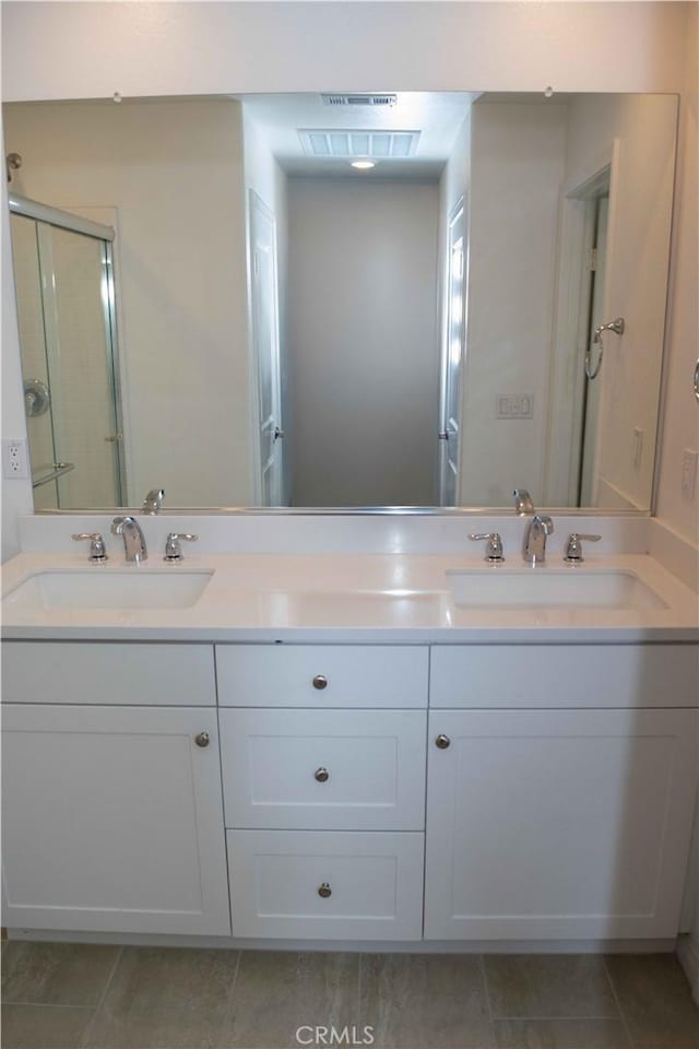bathroom with tile patterned floors, visible vents, a sink, and a stall shower