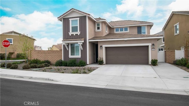 traditional home with stucco siding, fence, driveway, and a garage