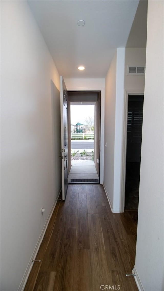 corridor featuring dark wood-style flooring, baseboards, visible vents, and recessed lighting