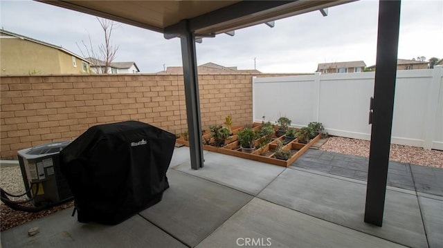 view of patio featuring a fenced backyard, a grill, a garden, and central AC
