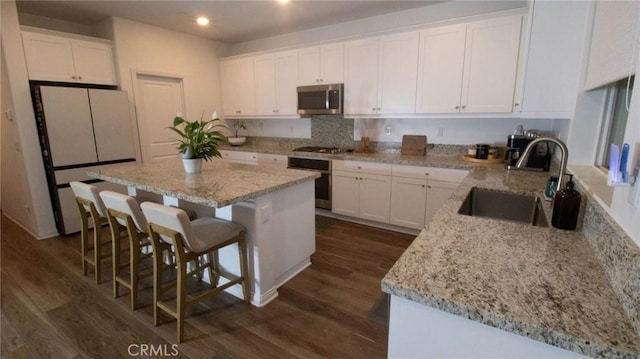 kitchen featuring dark wood-style flooring, appliances with stainless steel finishes, a sink, white cabinets, and recessed lighting