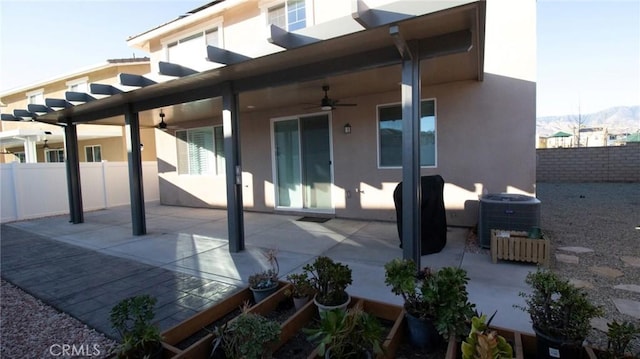 rear view of house with ceiling fan, stucco siding, and fence