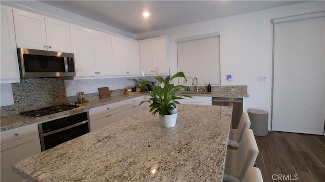 kitchen with gas cooktop, dark wood finished floors, wall oven, stainless steel microwave, and white cabinetry