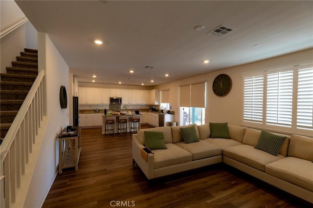 living room with visible vents, recessed lighting, dark wood finished floors, and stairway