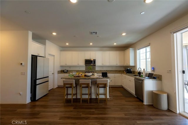 kitchen with a sink, a center island, white cabinets, and stainless steel appliances
