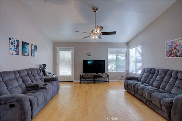 living area featuring light wood finished floors, baseboards, vaulted ceiling, and ceiling fan