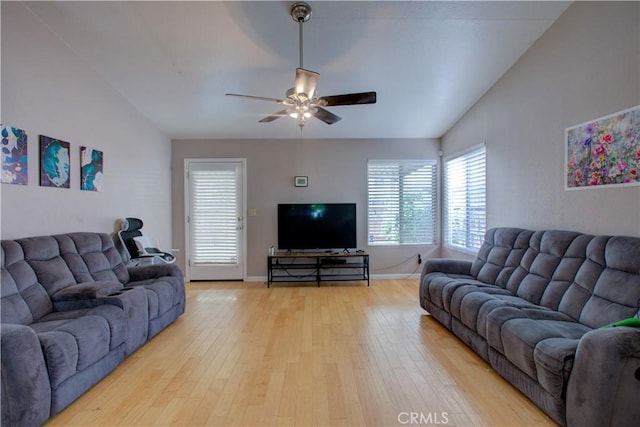 living room featuring baseboards, a ceiling fan, vaulted ceiling, and light wood-type flooring