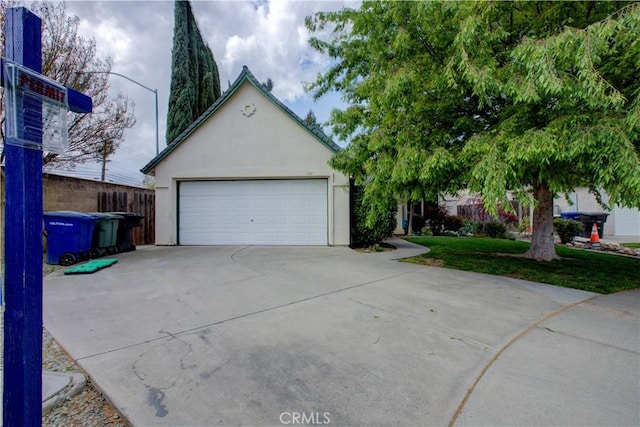 view of front of home with stucco siding, driveway, a garage, and fence