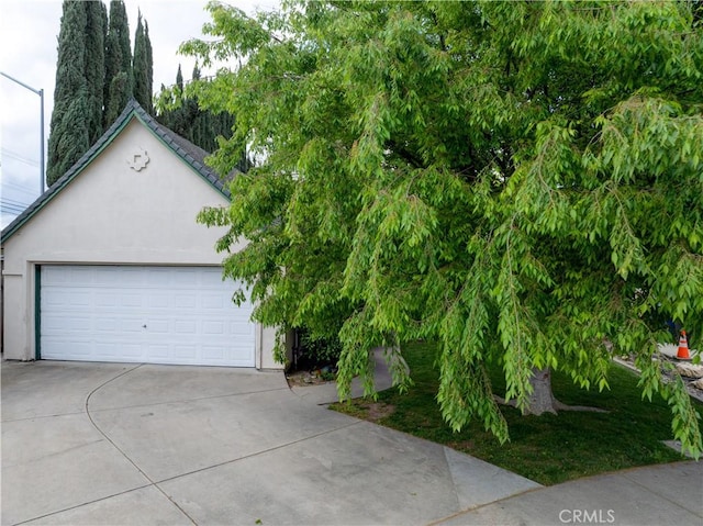 view of front of house featuring a garage, concrete driveway, and stucco siding
