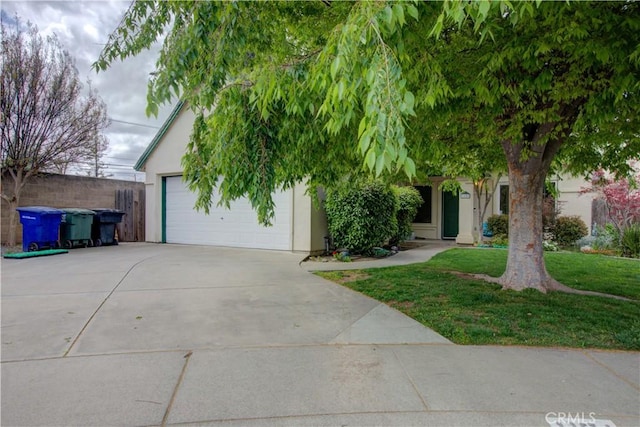obstructed view of property with a front yard, stucco siding, and concrete driveway