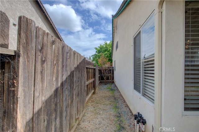 view of side of home with a fenced backyard and stucco siding