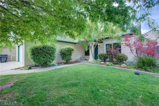 view of front facade featuring stucco siding, concrete driveway, and a front yard