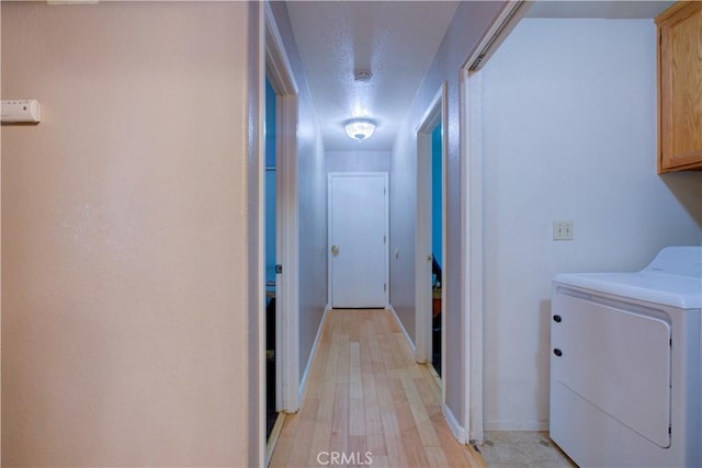 washroom featuring baseboards, a textured ceiling, light wood finished floors, cabinet space, and washer and dryer