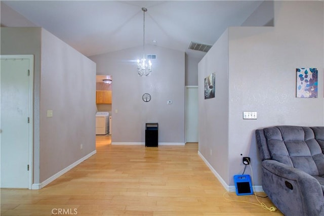 living area featuring visible vents, washer / clothes dryer, lofted ceiling, light wood-type flooring, and an inviting chandelier