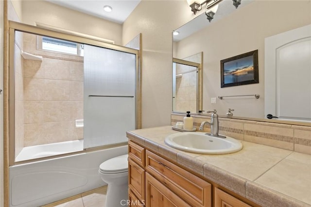 full bath with bath / shower combo with glass door, vanity, toilet, and tile patterned floors