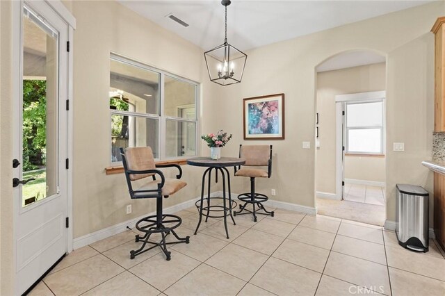 dining space with arched walkways, a chandelier, baseboards, visible vents, and light tile patterned flooring