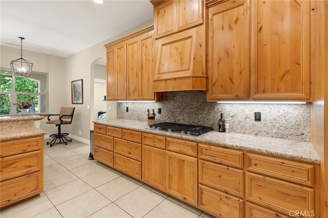 kitchen featuring light tile patterned floors, decorative backsplash, arched walkways, decorative light fixtures, and stainless steel gas cooktop