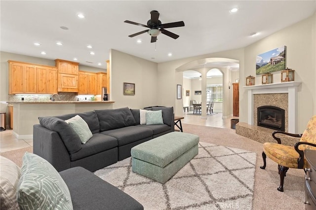 living room featuring recessed lighting, a fireplace, light tile patterned flooring, ceiling fan, and arched walkways