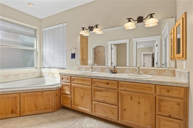 bathroom featuring a bath, tile patterned flooring, double vanity, and a sink