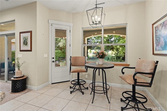 dining area featuring tile patterned floors, baseboards, and a notable chandelier