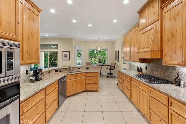 kitchen with recessed lighting, a peninsula, appliances with stainless steel finishes, and a sink