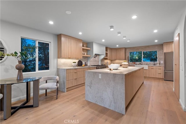 kitchen featuring modern cabinets, stainless steel refrigerator, open shelves, and light brown cabinets