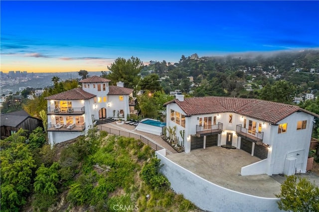 back of property with a tile roof, a chimney, stucco siding, fence, and a balcony