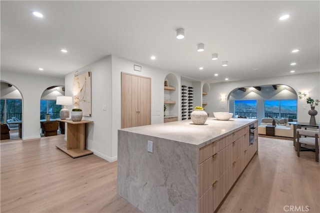 kitchen with modern cabinets, open floor plan, light wood finished floors, and a spacious island