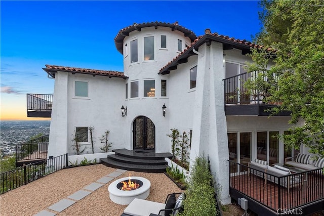 mediterranean / spanish-style house featuring a balcony, a tile roof, and stucco siding