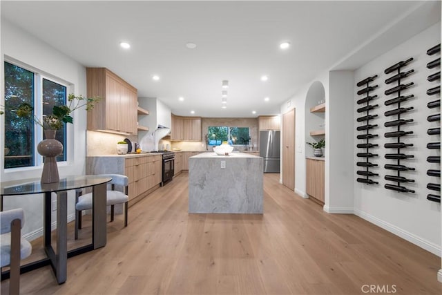 kitchen with light countertops, open shelves, a center island, freestanding refrigerator, and light brown cabinets