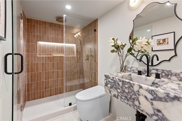 bathroom featuring a sink, toilet, and a stall shower
