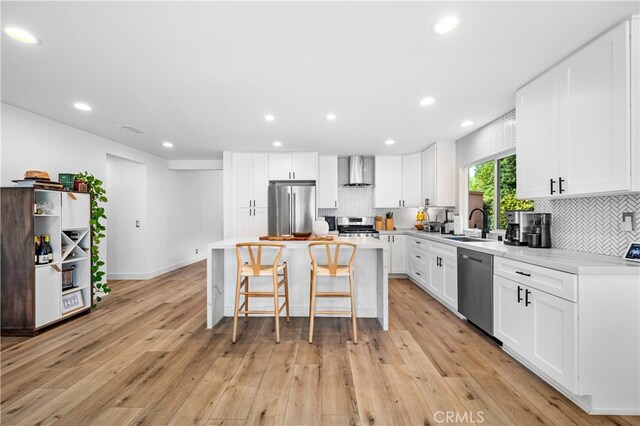 32772 Shipside Dr, Dana Point, CA 92629 - kitchen with wall chimney range hood, appliances with stainless steel finishes, a breakfast bar, light wood-style flooring, and light countertops