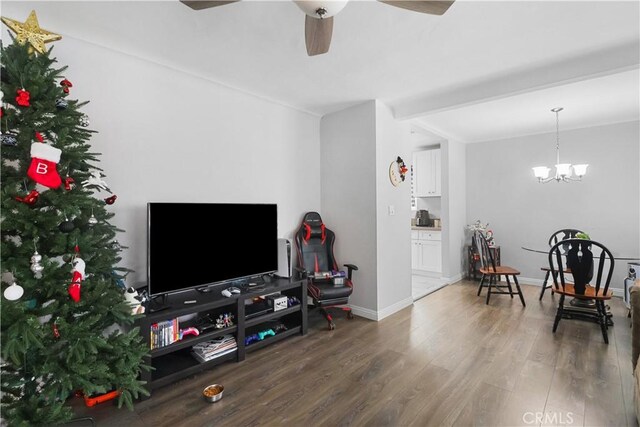 living area with wood finished floors, baseboards, and ceiling fan with notable chandelier
