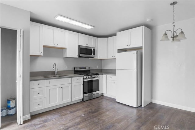 kitchen with stainless steel appliances, a sink, white cabinetry, a notable chandelier, and dark wood-type flooring