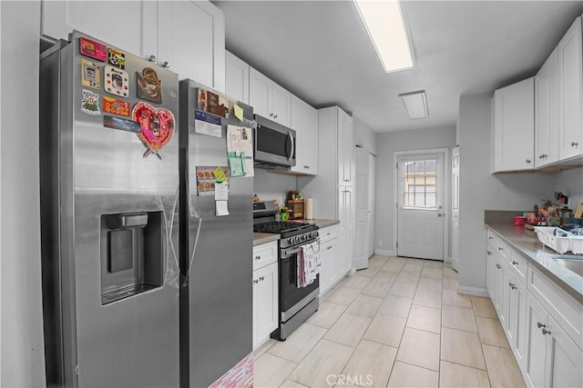 kitchen with baseboards, white cabinets, stainless steel appliances, and light countertops