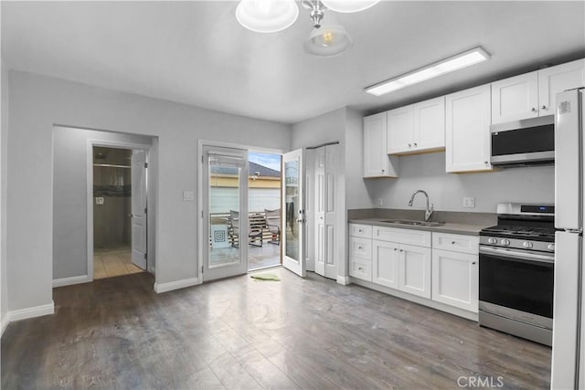 kitchen with white cabinetry, stainless steel appliances, baseboards, and a sink