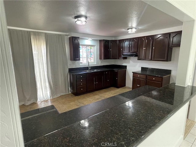 14802 Newport Unit 2B, Tustin, CA 92780 - kitchen featuring dark brown cabinets, dark stone counters, under cabinet range hood, and a textured ceiling