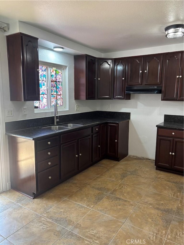 14802 Newport Unit 2B, Tustin, CA 92780 - kitchen with under cabinet range hood, dark countertops, dark brown cabinetry, and a textured ceiling