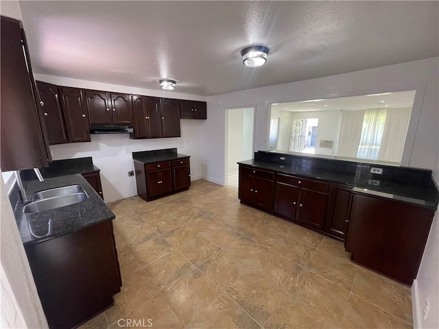 14802 Newport Unit 2B, Tustin, CA 92780 - kitchen with under cabinet range hood, dark countertops, dark brown cabinets, and a textured ceiling