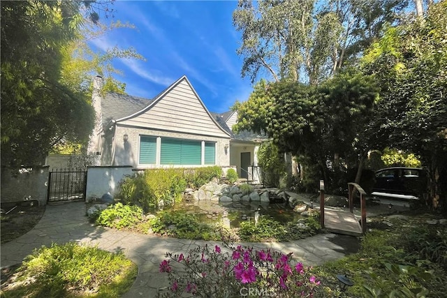view of front of home featuring a gate, stucco siding, a chimney, and fence