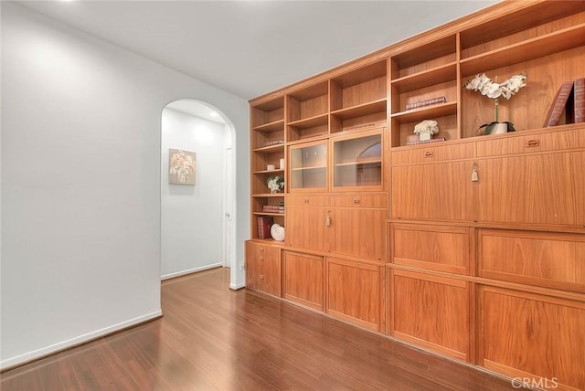interior space with dark wood finished floors, arched walkways, and baseboards