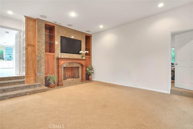 unfurnished living room with recessed lighting, a large fireplace, visible vents, and carpet