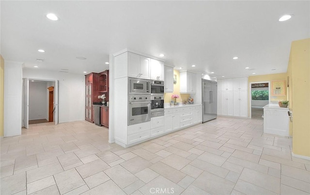 kitchen featuring built in appliances, white cabinets, recessed lighting, and light countertops