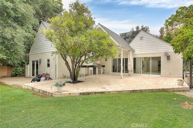 rear view of property with a yard, a patio area, and stucco siding