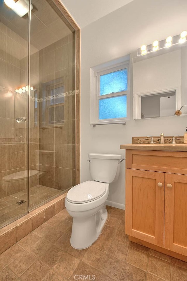 bathroom with tile patterned floors, toilet, vanity, baseboards, and a stall shower