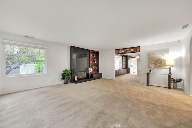 unfurnished living room with a healthy amount of sunlight, visible vents, and carpet