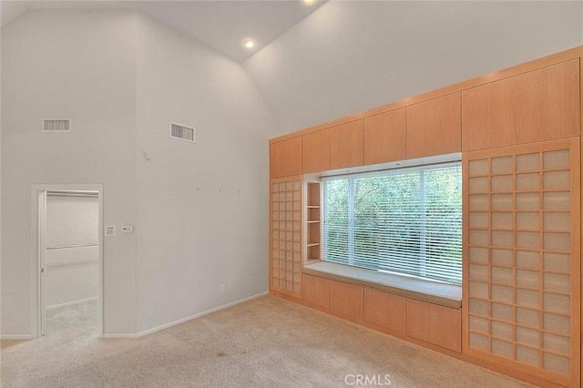 unfurnished room featuring visible vents, carpet flooring, and high vaulted ceiling