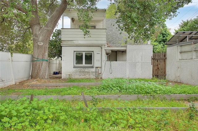 back of property with stucco siding, a shingled roof, and fence