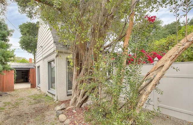 exterior space with a shingled roof, a fenced backyard, and stucco siding